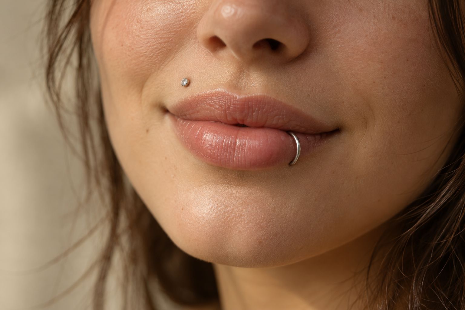Woman with a small stud above her upper lip and a silver hoop in her lower lip