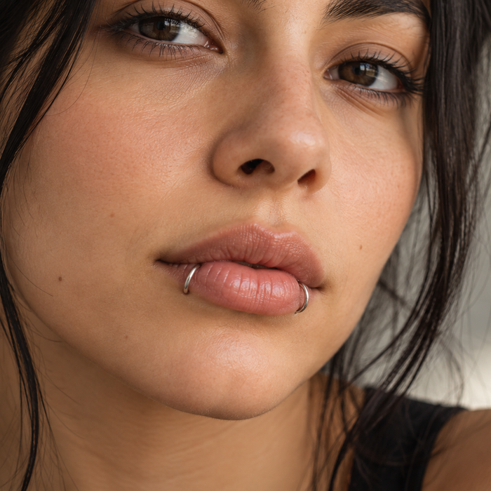 Woman with snake bite piercings: a silver hoop on each side of her lower lip