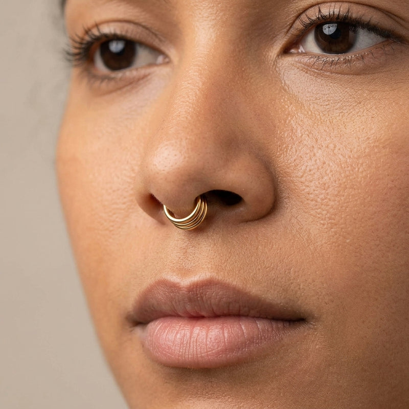 16G gold surgical steel triple layered hinge ring segment hoop, shown worn in a septum piercing.