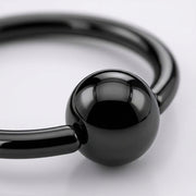 18G PVD coated steel nose ring with a glossy black fixed ball, close-up detail on a white background