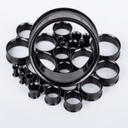 6G-1" PVD coated steel double flared eyelets with a black finish, assorted sizes in a pile, close-up detail