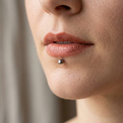 16G titanium lip ring with a shiny silver 3mm ball end, close-up shown worn in a labret piercing.