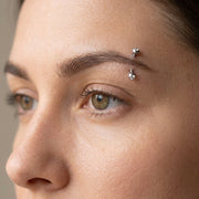 16G titanium curved eyebrow barbell with clear CZ gem balls, worn in an eyebrow piercing