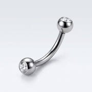 16G titanium curved eyebrow barbell with clear CZ gem balls, three-quarter view on white