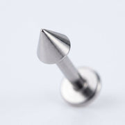 16G titanium labret stud with a sharp cone spike end and flat back, close-up angled view on a white background