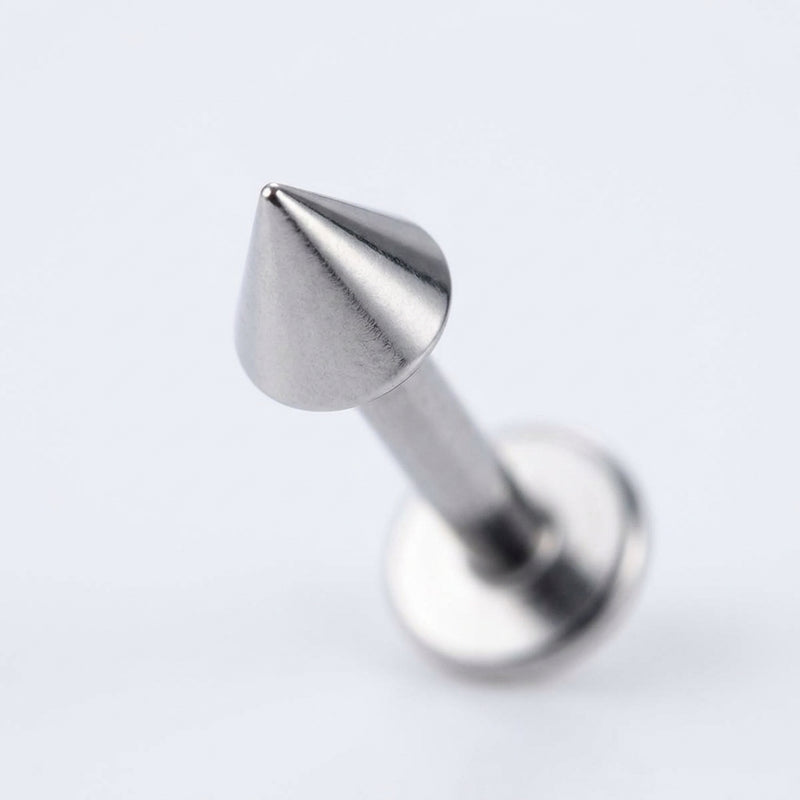 16G titanium labret stud with a sharp cone spike end and flat back, close-up angled view on a white background