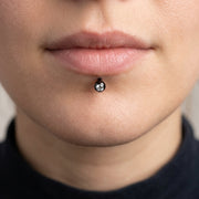 16G black surgical steel labret stud with a 3mm clear CZ gem ball, worn in a lip piercing