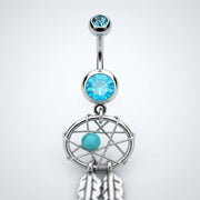 14G surgical steel belly ring with light blue gems, dream catcher dangle, and feather charms, close-up front view
