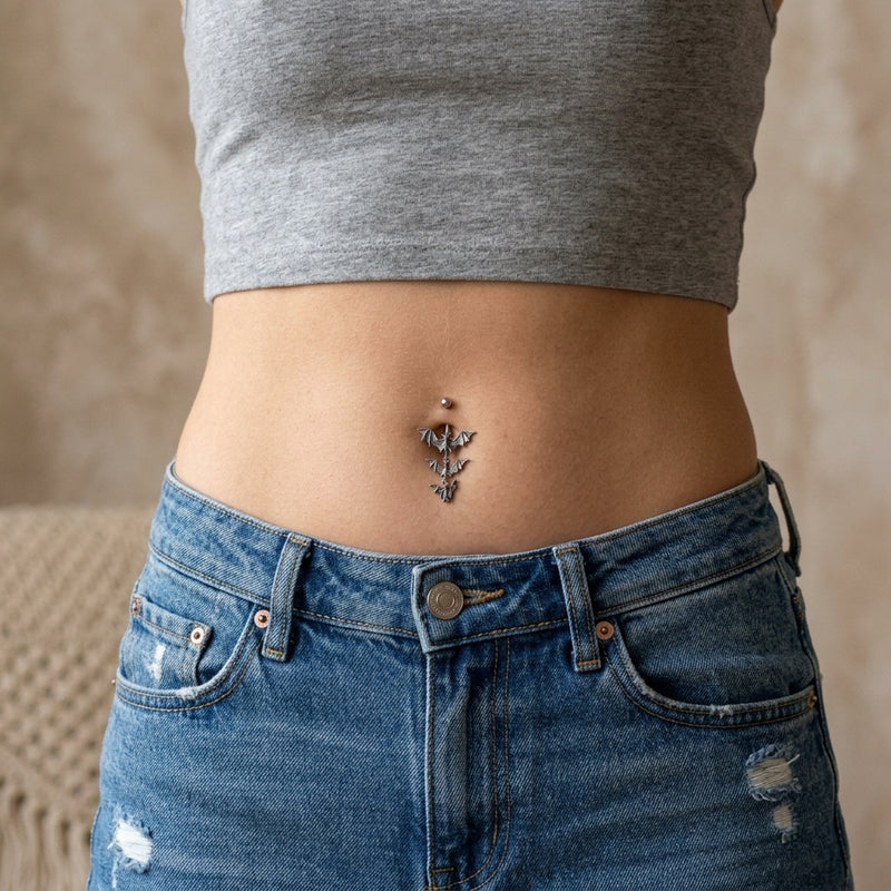 14G surgical steel navel ring with a triple gothic vampire bat dangle, shown worn in a navel piercing.