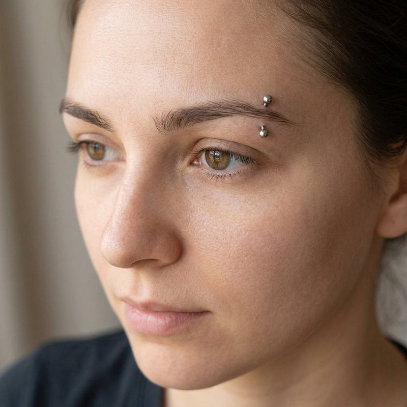 16G titanium curved eyebrow barbell with clear gem ball ends, worn in an eyebrow piercing