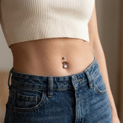 14G titanium curved navel ring with double clear CZ gems, shown worn in a navel piercing.