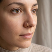 18G/20G gold titanium open nose ring adjustable half hoop, shown worn in a nostril piercing.