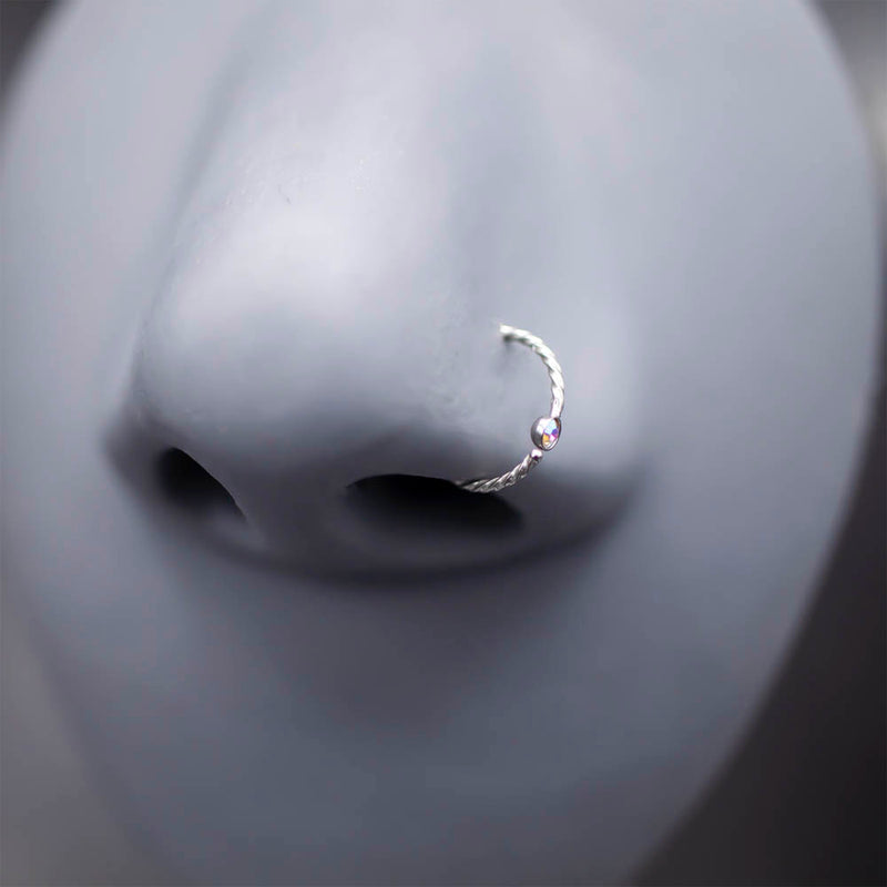 20G PVD coated surgical steel nose ring with twisted design and cubic zirconia gem ball for a stylish look.